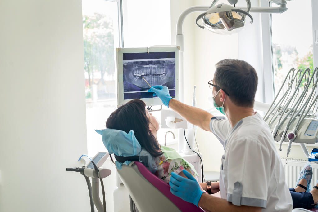 Doctor dentist showing patient's teeth on X-ray.